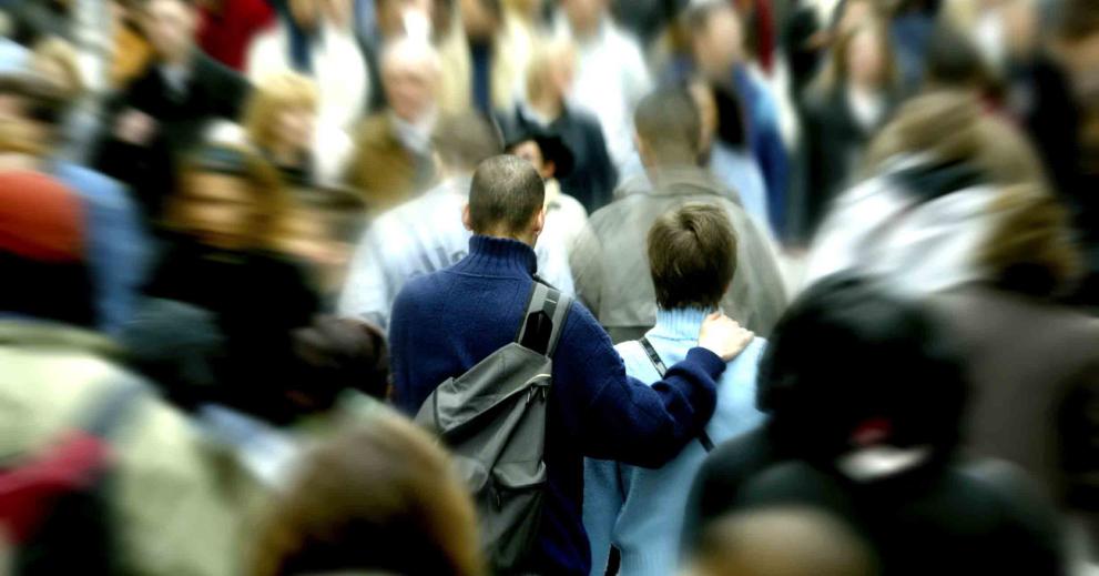 A woman and and man seen form the back in the middle of huge blur crowd