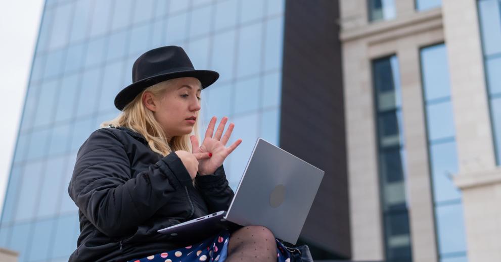 Woman using sign-language during a video-conference in front of its computer