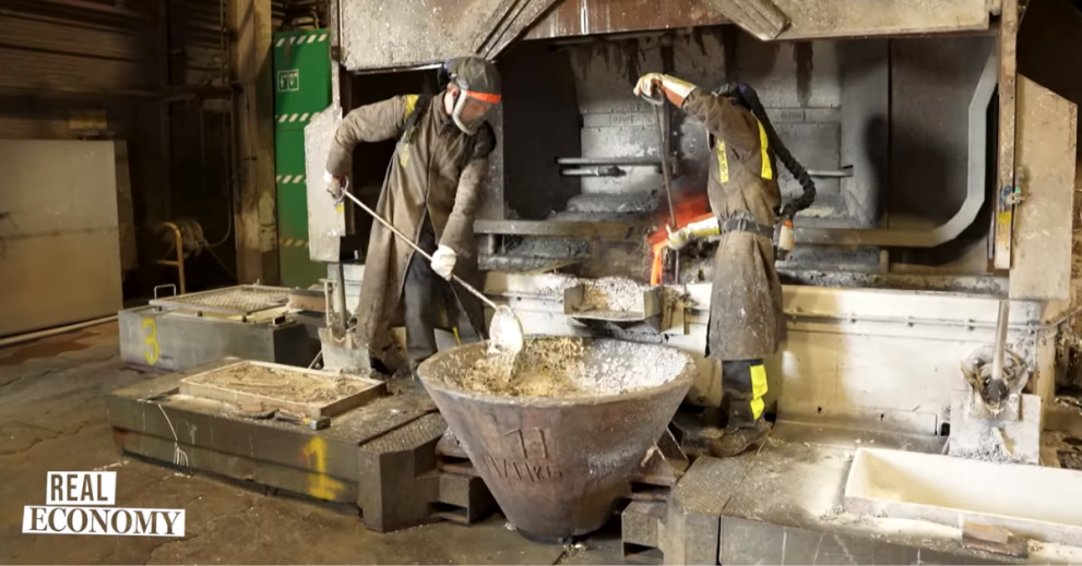 Screenshot from a Euronews report showing two worker in a recycling plant dealing with lead and other chimicals