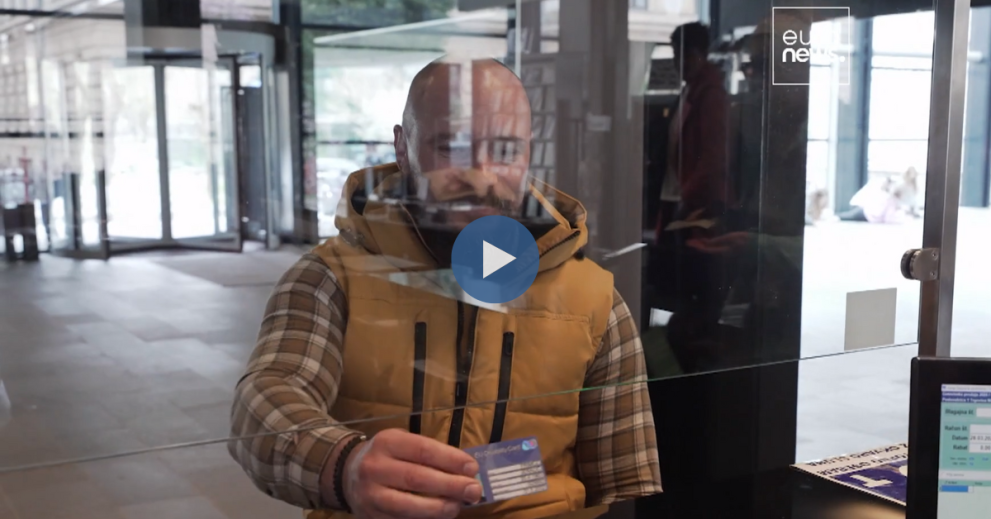 A man presents his EU Disability card to the cashier at a metro station.